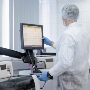 Scientist working in a lab adjusting equipment for research purposes, ensuring safety protocols.